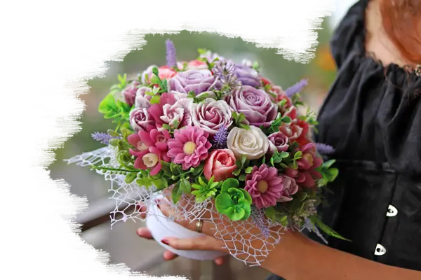 Sieviete tur rokās ziepju ziedu pušķi